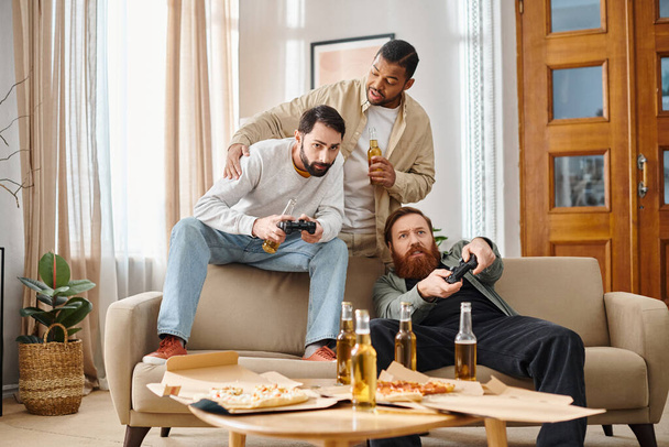Deux hommes de races différentes sont assis sur un canapé, concentrés et engagés dans un jeu vidéo, leurs expressions montrant l'excitation et la camaraderie. - Photo, image