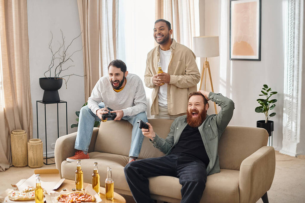 Два межрасовых мужчины в повседневной одежде сидят на диване, разделяя смех и товарищество в уютной гостиной. - Фото, изображение