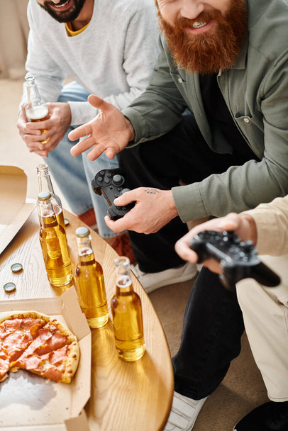 Kaksi miestä syventynyt videopelejä, nauttien olutta rento kotiympäristössä, mukana niiden rotujenvälinen ystävä. - Valokuva, kuva