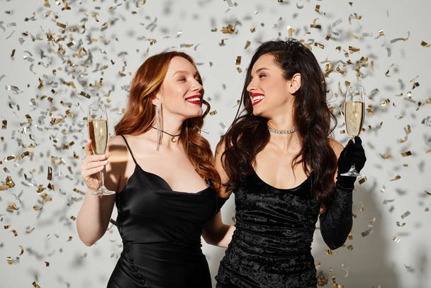 Две элегантные влюблённые женщины с радостью держат бокалы для вина. - Фото, изображение