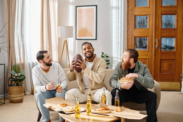 Tres hombres alegres, interracial en atuendo casual disfrutando de pizza juntos alrededor de una mesa en un ambiente acogedor. - Foto, Imagen