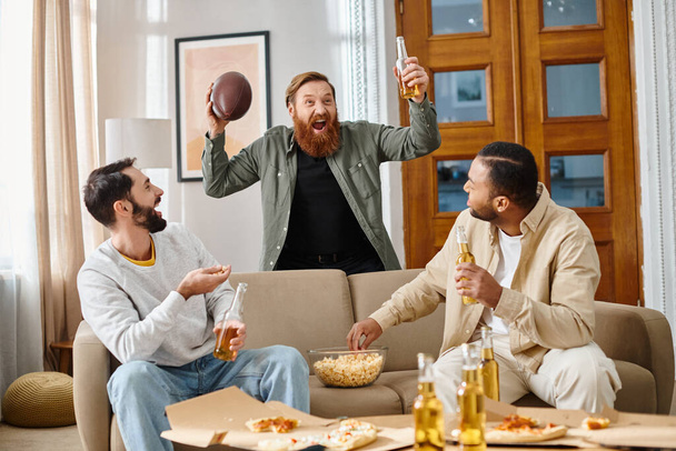 Три веселі, красиві чоловіки різних національностей, що сидять на дивані вдома, насолоджуються компанією один одного в повсякденному вбранні. - Фото, зображення