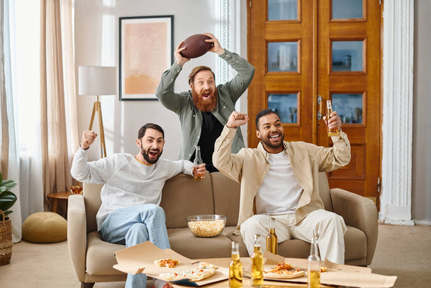 Three cheerful, interracial men in casual attire sit together on top of a couch, enjoying a great time in each others company. - Photo, Image