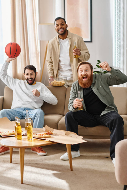Три веселих, красивих чоловіки різних рас насолоджуються компанією один одного в затишній вітальні, демонструючи дружбу і релаксацію. - Фото, зображення