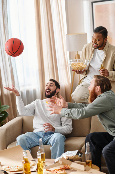 Tres hombres alegres e interraciales en atuendo casual juegan un juego competitivo de baloncesto, mostrando amistad y trabajo en equipo. - Foto, Imagen