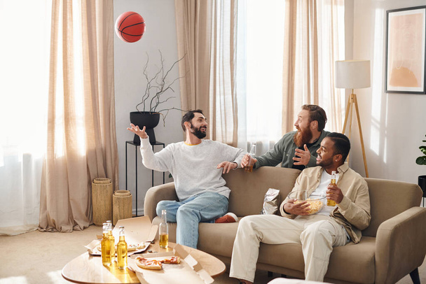 Três homens bonitos de raças diferentes sentam-se felizes e relaxam em cima de um sofá em um ambiente caseiro casual. - Foto, Imagem