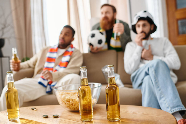 Drie divers, vrolijk mannen genieten van elkaars gezelschap rond een tafel, flesjes bier delend. - Foto, afbeelding