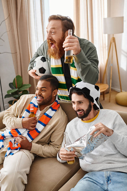 Drei gut aussehende, fröhliche Männer verschiedener Ethnien sitzen auf einer Couch und strahlen Wärme und Freundschaft in einem lässigen Ambiente aus.. - Foto, Bild