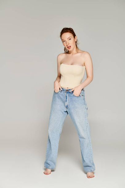 Una mujer emana confianza en jeans y camiseta sin mangas, posando. - Foto, Imagen