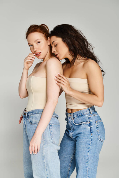 Two women, a loving lesbian couple, standing side by side in jeans, posing happily. - Foto, imagen