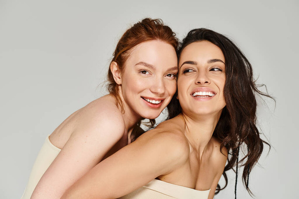 Zwei elegante Frauen umarmen sich und lächeln freudig. - Foto, Bild