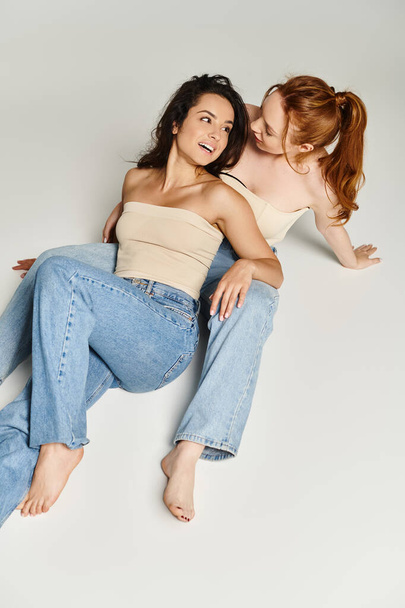 Zwei elegante Frauen liegen auf dem Boden, umarmen sich in liebevoller Umarmung. - Foto, Bild