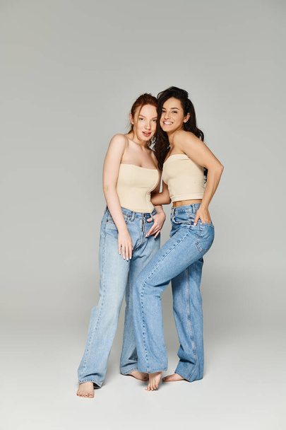 Dwie kobiety w dżinsach, kochająca para lesbijek, stojące razem szczęśliwie. - Zdjęcie, obraz