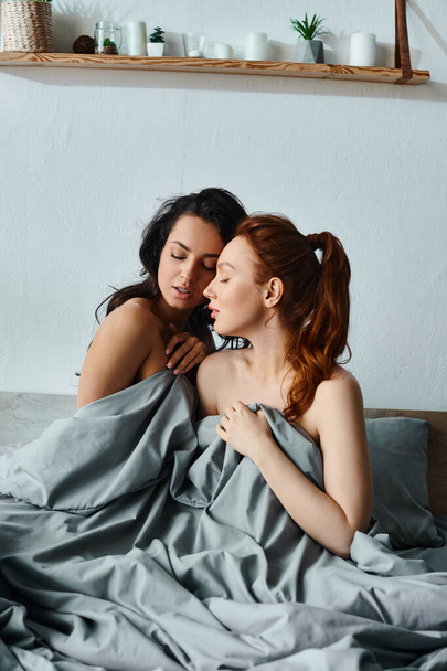 エレガントな服装の2人の女性,毛布に包まれたベッドの上に横たわる. - 写真・画像