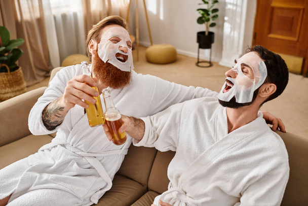 Dois homens alegres em roupões de banho relaxam em um sofá, desfrutando um do outro companhia e camaradagem. - Foto, Imagem