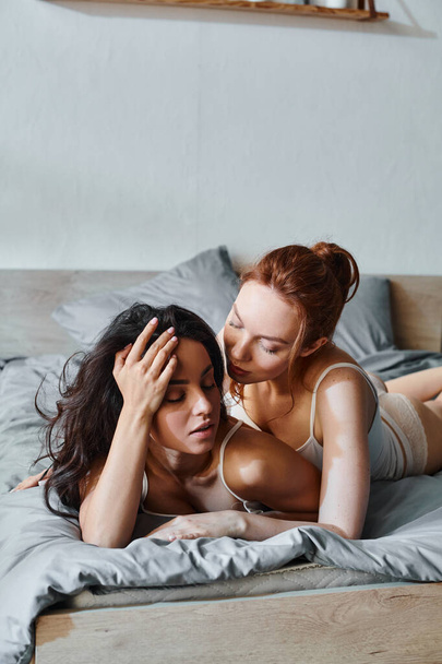 Due donne sofisticate in elegante abbigliamento sdraiate serenamente su un letto insieme. - Foto, immagini
