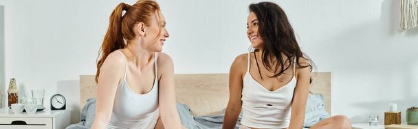 Dos mujeres elegantes sentadas en una cama entablando una conversación profunda. - Foto, Imagen