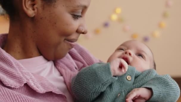 Μέση closeup της νεαρής όμορφη Αφροαμερικανή γυναίκα κρατώντας και λικνίζοντας μωρό γιο κλάμα στο σπίτι - Πλάνα, βίντεο