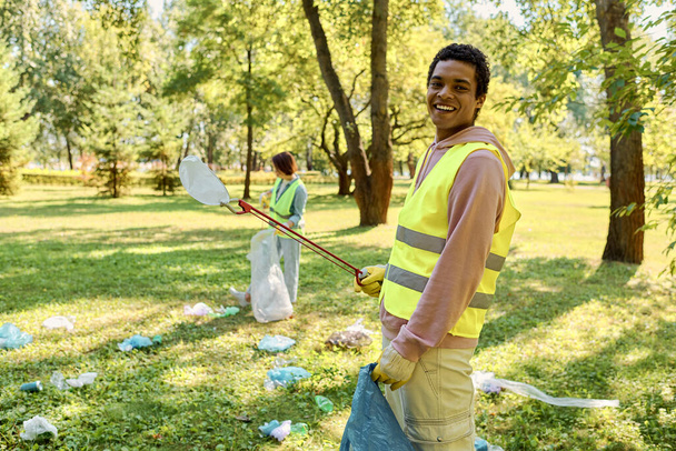 Socially active diverse loving couple in safety vests and gloves cleaning a park - Photo, Image