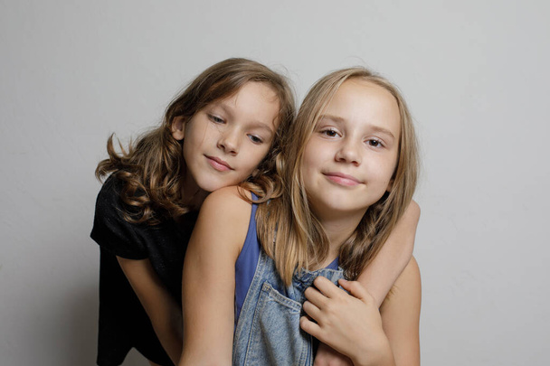 Sweet children sisters friends hugging on white studio wall banner background, fashion portrait   - Photo, Image