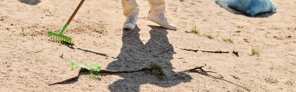Ένα άτομο κομψά σαρώνει με μια σκούπα ενώ ένα άλλο σφουγγαρίζει αποτελεσματικά με μια σφουγγαρίστρα σκόνης σε ένα πάρκο. - Φωτογραφία, εικόνα