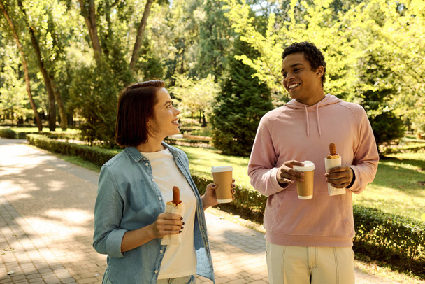 公園で一緒にコーヒーを楽しむ活気に満ちた服装のカップル,愛と団結を表現する. - 写真・画像