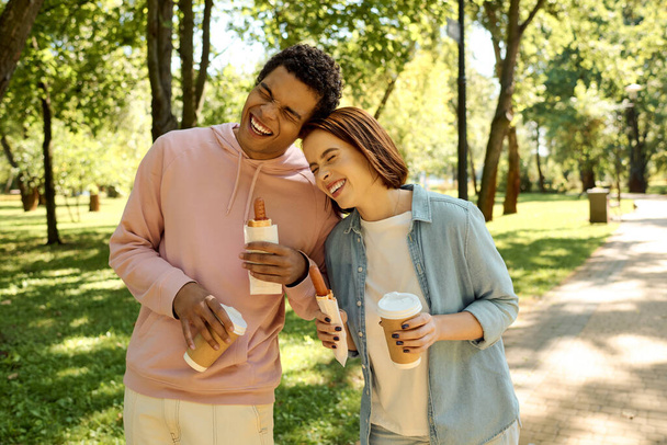 Ένας άντρας και μια γυναίκα, ντυμένοι με ζωντανή ενδυμασία, στέκονται κοντά σε ένα πάρκο, αποπνέοντας αγάπη και συντροφικότητα.. - Φωτογραφία, εικόνα