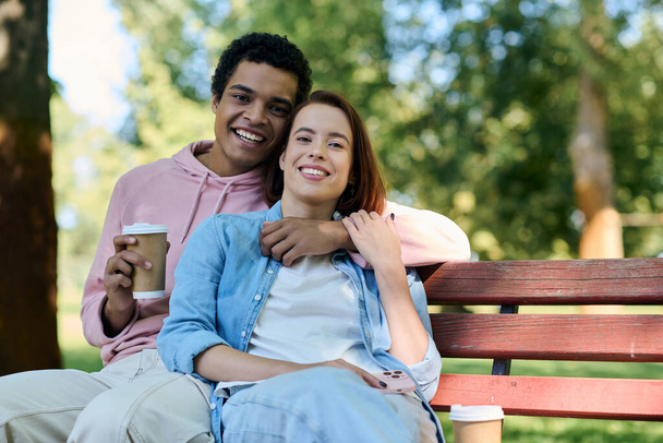 Una pareja diversa en traje vibrante se sienta junta en un banco del parque, disfrutando de la compañía de los demás en un entorno sereno. - Foto, imagen