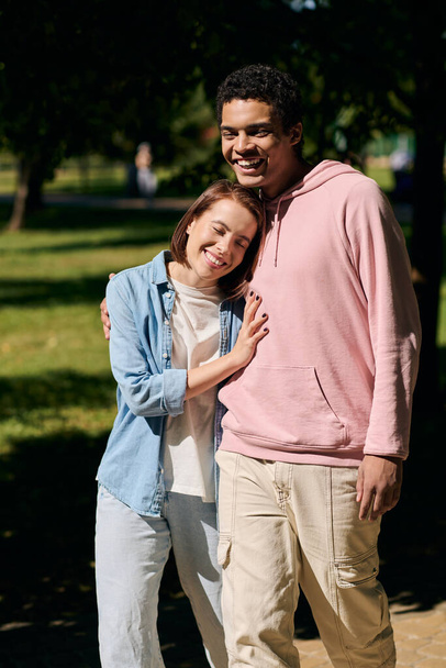 Un uomo e una donna, indossando abiti vibranti, stanno fianco a fianco in un parco, trasudando amore e felicità nella loro presenza diversificata.. - Foto, immagini