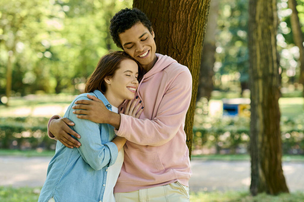 Un uomo in abiti vibranti abbraccia amorevolmente una donna, circondato dalla bellezza di un parco. - Foto, immagini