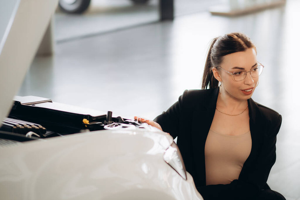 egy nő néz egy autó motor egy autó kereskedés - Fotó, kép