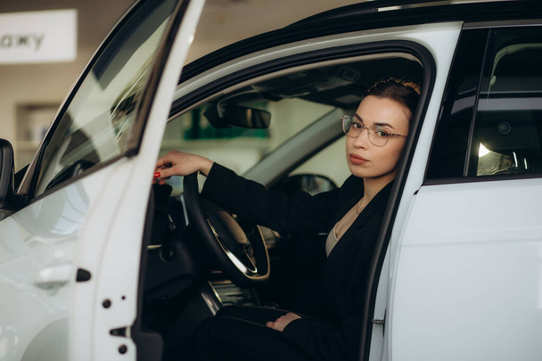 Jovem mulher em um showroom carro escolhendo um carro. Foto de alta qualidade - Foto, Imagem