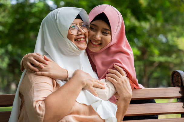 イスラム教徒の注意深い介護者や看護師は,病院の公園で患者の世話をする. ヒジャブでハッピーイスラム教徒の母親が娘を抱きしめる. 貯蓄と高齢者健康保険,幸せな家族の概念 - 写真・画像