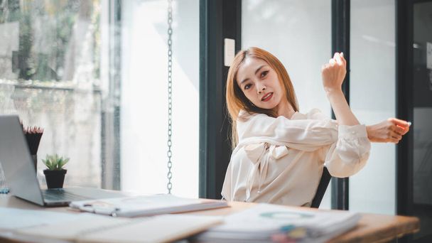 Business analytics concept, Una giovane donna asiatica professionale che si prende una pausa per distendersi nella sua ben organizzata postazione di lavoro in ufficio - Foto, immagini