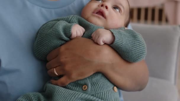 Medio primer plano de la joven mujer negra regocijada sosteniendo al bebé en brazos y besándolo en su pequeña frente - Metraje, vídeo