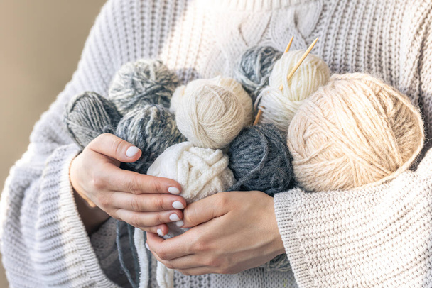 Gros plan, les mains de la femme portant un pull en laine tenant plusieurs boules de fil colorées. Loisirs féminins tricot. - Photo, image