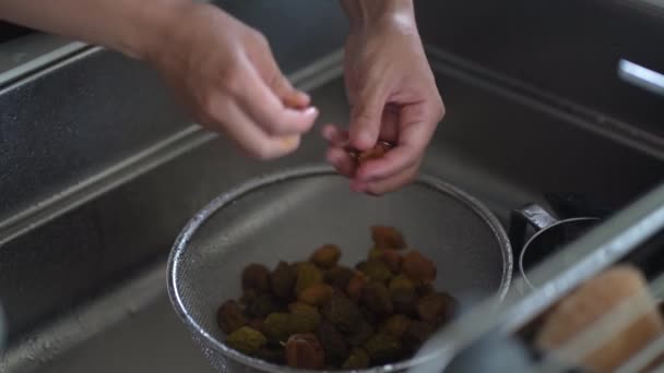 A woman removes seeds from plum fruit taken out from plum syrup - Footage, Video