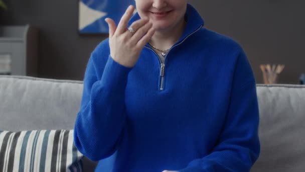 Colpo ritagliato di giovane donna caucasica che indossa maglione blu elettrico a maglia con cerniera guardando la fotocamera fare gesti mano, comunicando con l'aiuto del linguaggio dei segni - Filmati, video
