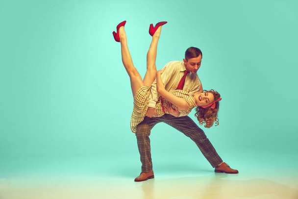 Retrato dinámico de pareja feliz realizando animados movimientos de baile swing en movimiento contra el gradiente fondo de menta. Concepto de ritmo musical, arte, energía, felicidad, hobby, humor, acción - Foto, imagen