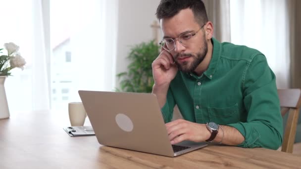 homem adulto caucasiano com barba e óculos de trabalho no laptop em casa  - Filmagem, Vídeo
