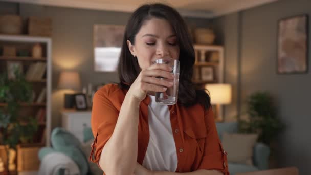 γυναίκα όμορφη νεαρή γυναίκα σταθεί στο σπίτι με ένα ποτήρι νερό ποτό - Πλάνα, βίντεο