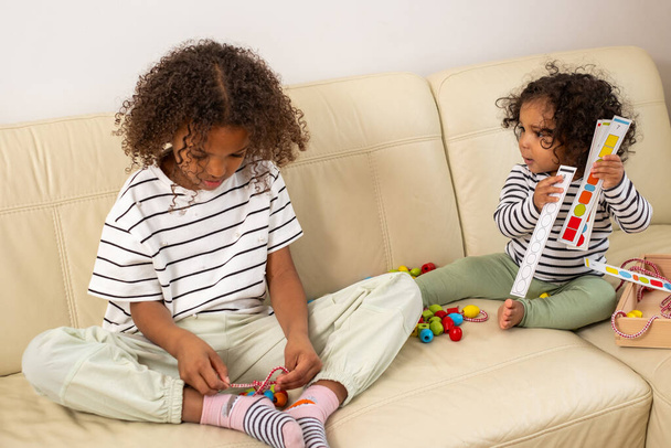 Twee Afro-Amerikaanse meisjes worden geabsorbeerd in het spel met ontwikkelingsprovocatief speelgoed. Betrokkenheid, en interesse in het leren perfect voor kind beroep ideeën. Hoge kwaliteit foto - Foto, afbeelding