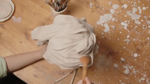 Top kilátás felismerhetetlen kéz szobrász tisztító agyag női fej szobor forgó stand ecsettel, miközben kézműves műhelyben - Felvétel, videó
