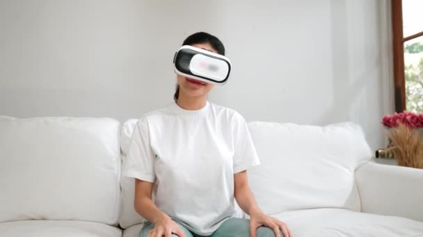 Junge Frau nutzt Virtual-Reality-VR-Brille zu Hause für lebhaftes Online-Shopping-Erlebnis. Virtual-Reality-VR-Innovation optimiert für weiblichen digitalen Unterhaltungsstil. - Filmmaterial, Video