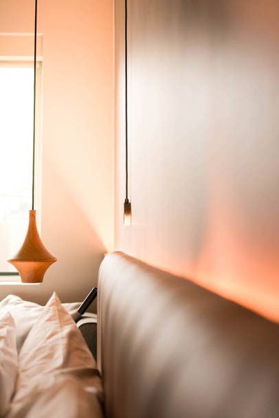 Ένα δωμάτιο ξενοδοχείου διαθέτει ένα άνετο κρεβάτι και μια λάμπα φωτισμού με χώρο αντίγραφο - Φωτογραφία, εικόνα
