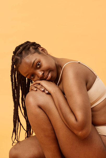 Estúdio vertical retrato de jovem afro-americana com cabelo trançado vestindo lingerie confortável posando para câmera, espaço de cópia - Foto, Imagem