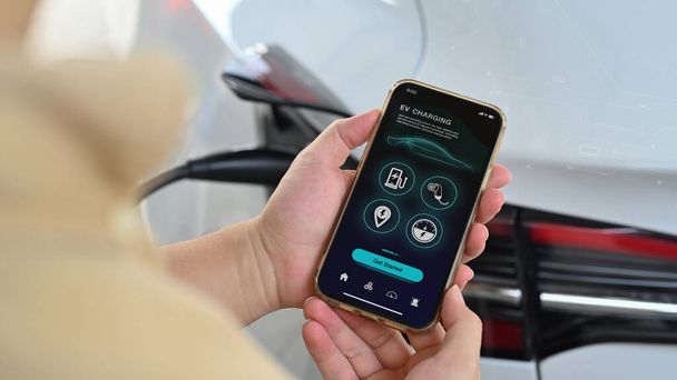 Empresário segurando smartphone com aplicativo móvel inteligente EV. - Foto, Imagem