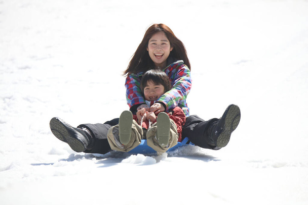 Parent and child playing on a sled - Photo, Image