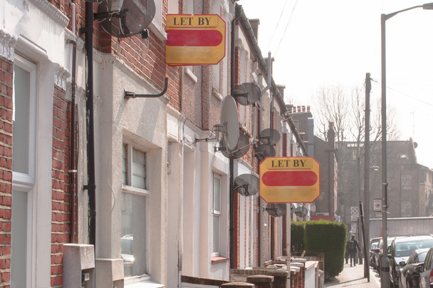 Агент по недвижимости "пропускает" вывески вдоль дороги в пригороде Лондона
 - Фото, изображение