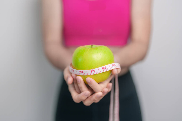 жіноча рука тримає зелене яблуко, щаслива жіноча фітнес-вибір фруктів здорове харчування. Контроль над дієтою, втрата ваги, ожиріння, харчування та концепції харчування - Фото, зображення
